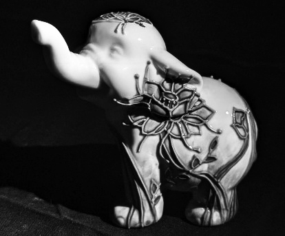 A ceramic elephant with its trunk in the air in the style of photographer Edward Weston.